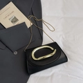 Elegant black leather crossbody bag with a large gold ring buckle and sleek snake chain - Black