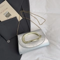 Silver leather chain clutch bag with unique gold clasp on a minimalist grey background - Silver