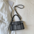 Detailed view of the striped woven texture and adjustable shoulder strap of the handbag - Black