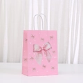 Pink paper gift bag with sweet bow prints and white twisted handles on clean background - White Plaid Style (488-1) / 21x15x8cm