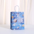 Detail van blauwe astronauten cadeautas met ONE tekst en witte papieren handvatten - Astronaut Sterrenhemel ONE Stijl (496-6) / 21x15x11cm