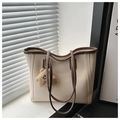 Dettaglio di una borsa tote crema con bordo marrone e ciondolo a forma di orsetto di peluche - Con Ciondolo / Bianco