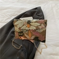 Borsa a busta verde scuro con paillettes floreali e catena dorata tenuta in mano - Marrone
