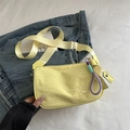 Pale yellow canvas crossbody pillow bag with wide strap and woven rope charm detail - With Charm / Yellow