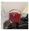 Détail d'un sac à main léopard rouge avec finition vernie et boucle dorée en forme de V - Rouge