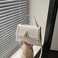 White minimalist crossbody handbag for women with large gold V-shaped metal buckle detail - White