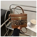 Detail of leopard print bucket bag featuring brown leather trim and dual metal zippers - Brown