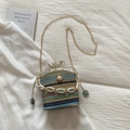 Close-up of multicolored straw bucket bag featuring a large pearl and gold chain strap - Blue