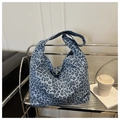 Detailansicht einer blauen Canvas-Tasche mit Leopardenmuster auf einem Metallregal - Blau