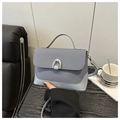 Detailed close-up of blue knit shoulder bag with silver horseshoe buckle and handle - Blue