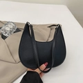 Bolso medialuna negro minimalista con textura de lichi sobre un fondo de blazer chic - Negro