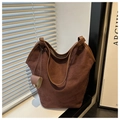 Gros plan sur le cabas en daim marron avec finitions en cuir lisse et pendentif - café