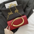 Pochette rouge chic avec boucle dorée et bandoulière chaîne sur une veste grise - Rouge