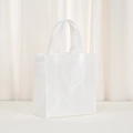 Detail of white non-woven gift bag showing square textured pattern and glossy finish - White