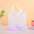Detalle de bolsa de regalo degradada morada con asas de cinta y letras doradas de arte - Púrpura estrellado