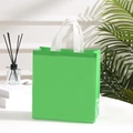 Detail view of bright green non-woven shopping bag with white handles in a lifestyle setting - 29*27*12cm / Green