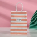 Detalle de bolsa de regalo de papel kraft a rayas naranjas y blancas con estampado Thank You - Rayas Rosa Blanco