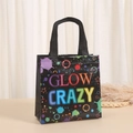 Detail of black non-woven gift bag with vibrant GLOW CRAZY neon text and star patterns - GLOW CRAZY Style