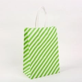 Detalle de bolsa de regalo de papel a rayas verdes y blancas con asas trenzadas - Verde