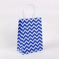 Detail der blau-weiß gewellten Papiertüte mit gedrehten Griffen für Geschenke - Chevron Dunkelblau