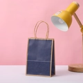Dettaglio di un sacchetto regalo in carta blu scuro con manici in carta kraft - Stile Blu Scuro / 21x15x8cm