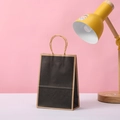 Dettaglio del sacchetto regalo in carta nera opaca con bordo kraft e manici in corda - Stile Nero / 21x15x8cm
