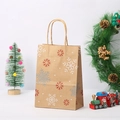 Detail view of brown kraft paper Christmas gift bag featuring white and red snowflake patterns - White Snowflake Pattern (019-4)