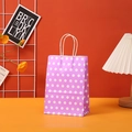 Purple polka dot kraft gift bag with white twist handles in a warm interior setting - 15x11x6cm / Purple