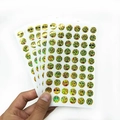 Vue rapprochée d'autocollants de récompense en feuille dorée avec divers visages emoji - Smiley