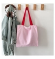 Detail van roze-wit gestreepte seersucker handtas met rood handvat aan een wandhaak - Roze Wit Gestreepte met Rood Handvat / Roze