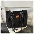 Detalle de bolso tote de pana negra con correa de cadena y parche de logo en cuero - Negro