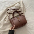 Bolso tipo cubo marrón con grabado FASHION y cierre dorado sobre una chaqueta - Marrón