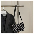 Detail of checkered tweed hobo bag with frayed edges hanging on a display stand - Black Grid