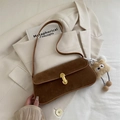 Brown suede baguette bag with gold buckle and plush charm on a beige blazer - Brown with Pendant