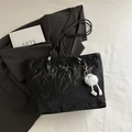 Large black textured tote bag with chic white plush charm and silver logo for commuting - Black With Pendant