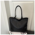 Close-up of black woven leather tote bag with knotted rope handles and textured finish - Black