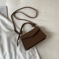Close-up of dark brown woven texture handbag with golden buckles on white fabric - Brown