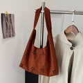Braune Wildleder-Einkaufstasche mit floralem Lochmuster in einem Modeatelier - Kaffee