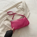 Glanzende roze laklederen baguette tas op een wit jasje, minimalistische stijl - rozenroze