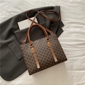 Bolso tote marrón con monograma y detalles dorados sobre una chaqueta gris - Marrón