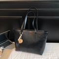 Bolso tote minimalista negro brillante con colgante sobre un escritorio blanco - Con Colgante / Negro