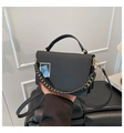 Close-up of black square bag with golden chain and blue textured metallic buckle detail - Black
