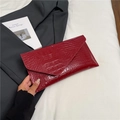 Deep red crocodile embossed envelope clutch bag held against a professional background - Red
