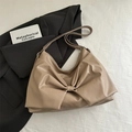 Borsa a spalla kaki minimalista con fiocco e tracolla larga su sfondo di tessuto bianco - Cachi