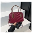 Macro view of V-quilted burgundy leather shell bag with gold hardware and brown handles - Burgundy