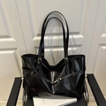 Glossy black large-capacity tote bag with gold buckles on a leather chair - Black