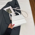 White trapezoidal crossbody bag with knotted handle detail on grey suit jacket - White