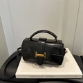 Bolso cuadrado de charol negro con cierre en T dorado sobre libros blancos - Negro