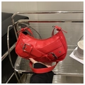 Detalle de un bolso baguette de cuero rojo con hebillas plateadas y remaches de metal - Rojo