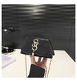 Close-up of black patent leather crossbody bag with gold S-buckle and tassel detail - Black